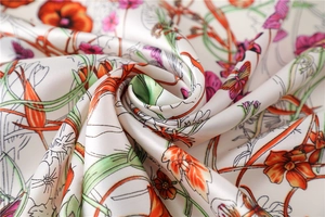 Macro shot of satin silk scarf with vibrant floral and butterfly prints and glossy texture