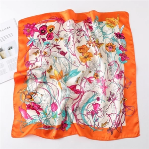 Detailed view of floral silk scarf featuring bright orange borders and satin finish