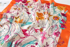 Detail of floral silk scarf with butterfly print and orange borders on white background
