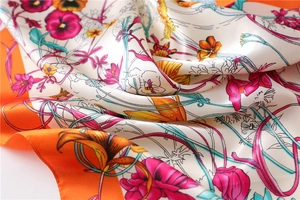 Macro detail of the smooth silk texture and vibrant floral print on the neck scarf