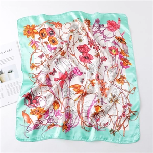 Detailed view of floral printed silk square scarf with mint green border and nature motifs