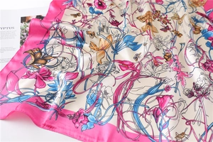 Detailed close-up of floral silk square scarf with pink border and butterfly prints