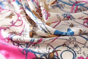 Detailed close-up of silky satin scarf featuring floral and butterfly prints with pink edges