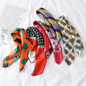 Detailed close-up of five colorful twilly silk scarves with diverse geometric and floral prints