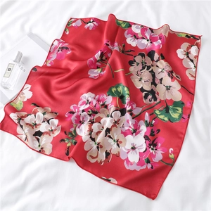 Detail of red floral square silk scarf with vintage flower patterns and satin texture