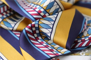Close-up of geometric pattern silk scarf with vibrant yellow and navy color blocks