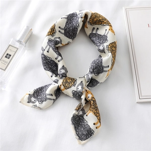 Detail of silk-like scarf with cartoon sheep print and neatly stitched edges on white fabric