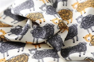 Detailed view of high-quality silk scarf fabric with hand-drawn sheep patterns and soft drape