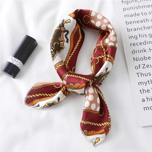 Close-up of knotted burgundy silk scarf with metal chain and buckle print details