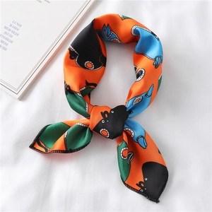 Close-up of silk square scarf with orange owl print and fine stitching on white fabric