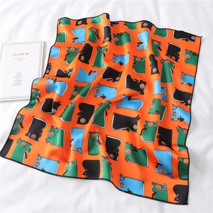 Detail of a square silk scarf with orange horse pattern on soft fabric background