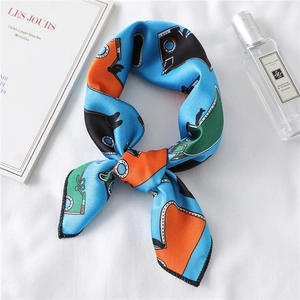 Close-up of knotted blue silk scarf with geometric patterns next to a perfume bottle