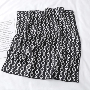 Detail of black and white chain-link silk scarf on textured fabric with a card