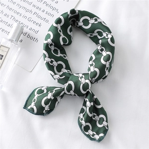 Elegant emerald green silk scarf with white chain pattern used as a stylish hair tie