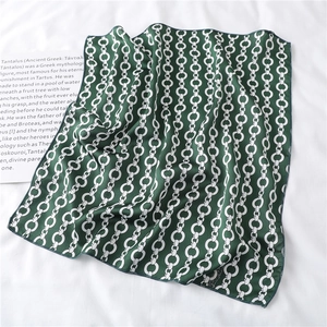 Detail of silk square scarf featuring green pattern and white chain links on white cloth
