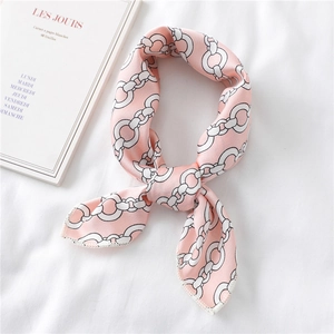 Close-up of pink silk square scarf featuring black and white chain patterns on fabric