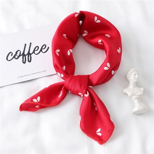 Close-up of red silk scarf with white heart patterns and smooth stitched edges