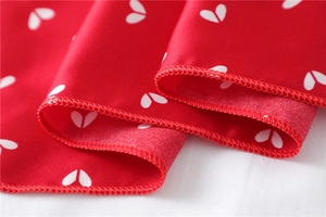 Macro shot of red silk scarf with white heart print and detailed stitched edges