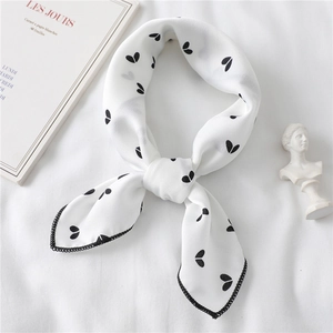 Elegant white silk scarf with black heart print tied in a knot on minimalist background