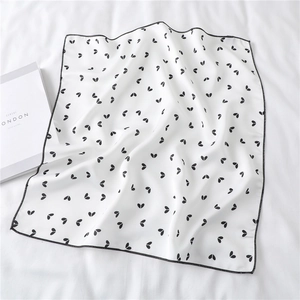 Detailed view of white silk scarf with black heart print and precise stitched edges