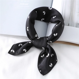 Detail view of a black satin scarf with white heart prints tied into a stylish bow knot