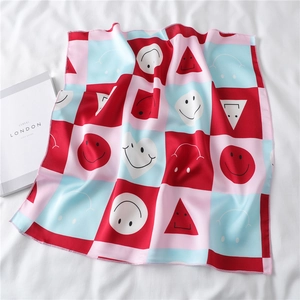 Detail of vibrant checkered satin scarf with smile and heart patterns on white fabric
