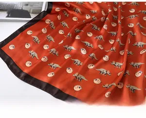 Detail shot of brick red cartoon dinosaur silk scarf with smooth satin finish and fine stitching