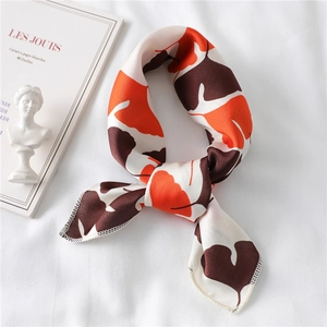 Close-up of elegant orange leaf pattern silk scarf with hand-rolled edges on art books