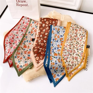 Détail de cinq foulards twilly étroits aux motifs floraux colorés sur tissu plissé