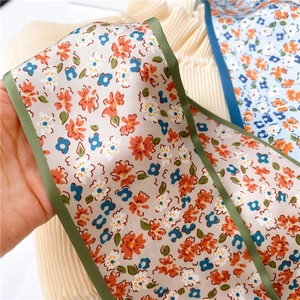 Détail d'un foulard étroit à fleurs avec passepoil en satin vert et texture lisse