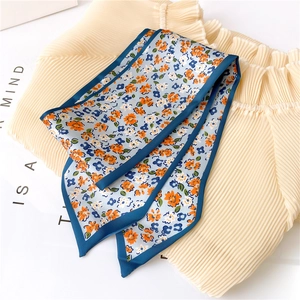 Vue détaillée du foulard en soie à fleurs orange sur tissu bleu clair avec bordure