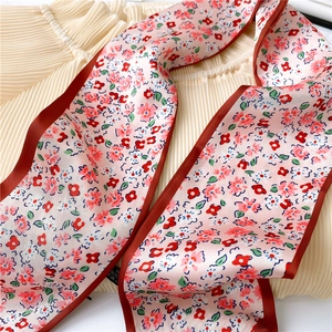 Gros plan d'un foulard étroit rose à fleurs avec des bords cousus rouge foncé