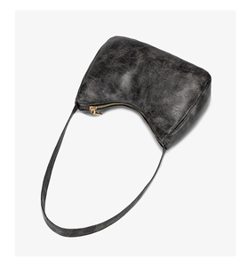 Détail de la texture cuir vintage et fermeture éclair dorée sur sac croissant noir