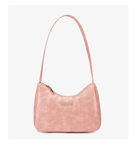 Détail de la texture similicuir rose rétro et zip doré sur un sac chic porté épaule