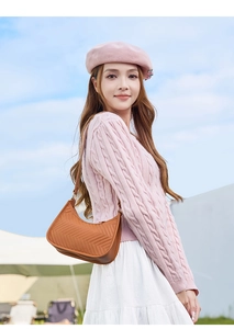 Close-up of brown quilted shoulder bag with V-shaped stitching on a pink knit sweater