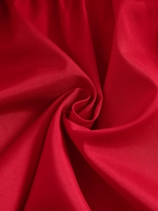 Detailed macro shot of vibrant red satin fabric with elegant spiral pleated texture