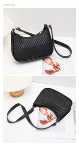 Detail view of black V-quilted faux leather crescent bag with gold-tone zipper and strap