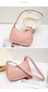 Detail view of pink quilted shoulder bag with V-shaped stitching and gold hardware