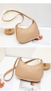 Close-up of beige minimalist underarm bag featuring elegant chevron quilted patterns