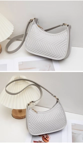 Close-up of light grey quilted shoulder bag with wave stitching and golden zipper detail