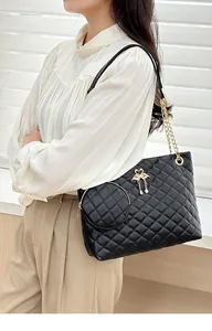 Detail of black quilted barrel bag with gold chain strap and mini round coin purse
