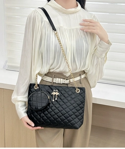 Detail of black quilted barrel bag with swan charm, gold chain and small round pouch