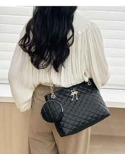 Close-up of black quilted cylinder bag with gold swan logo and detachable coin purse