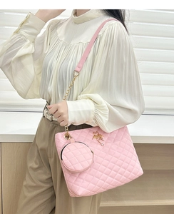Detail of pink quilted barrel bag featuring a gold swan logo and matching coin purse