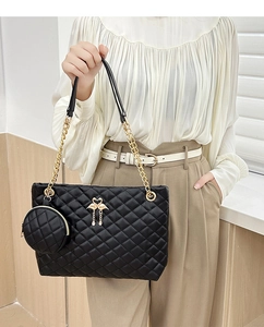 Detail of black quilted barrel bag with gold chain strap and flamingo charm accessory