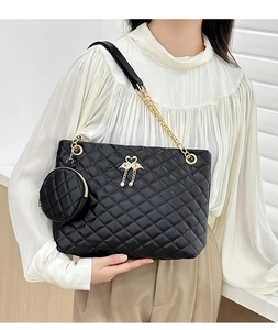 Black quilted cylinder bag with gold flamingo charm and metallic chain strap detail