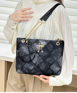 Detail of quilted denim cylinder bag featuring a gold swan charm and mini coin purse
