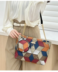Detail of checkered barrel bag with geometric patterns, chain strap and swan charm