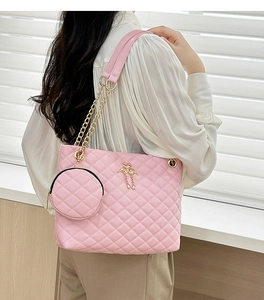 Detail of pink quilted barrel bag featuring golden swan buckle and chain strap
