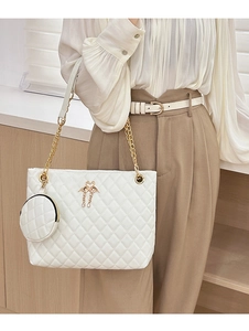 Detail of white quilted barrel bag with gold flamingo clasp and chain strap on a model
